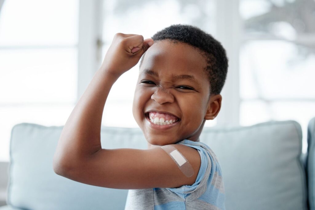 Grinning boy flexing his arm to show off a bandage